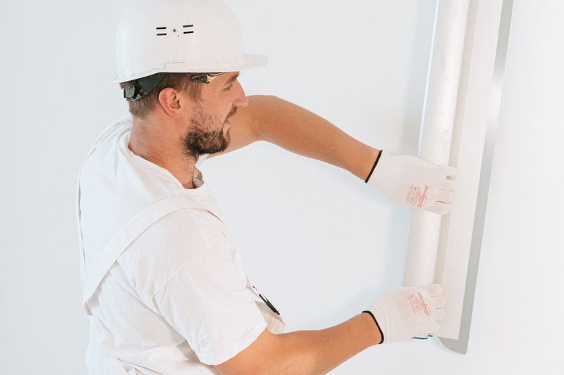 A finisher setting a sheet of board against the framing — {{SERVICE_1}}